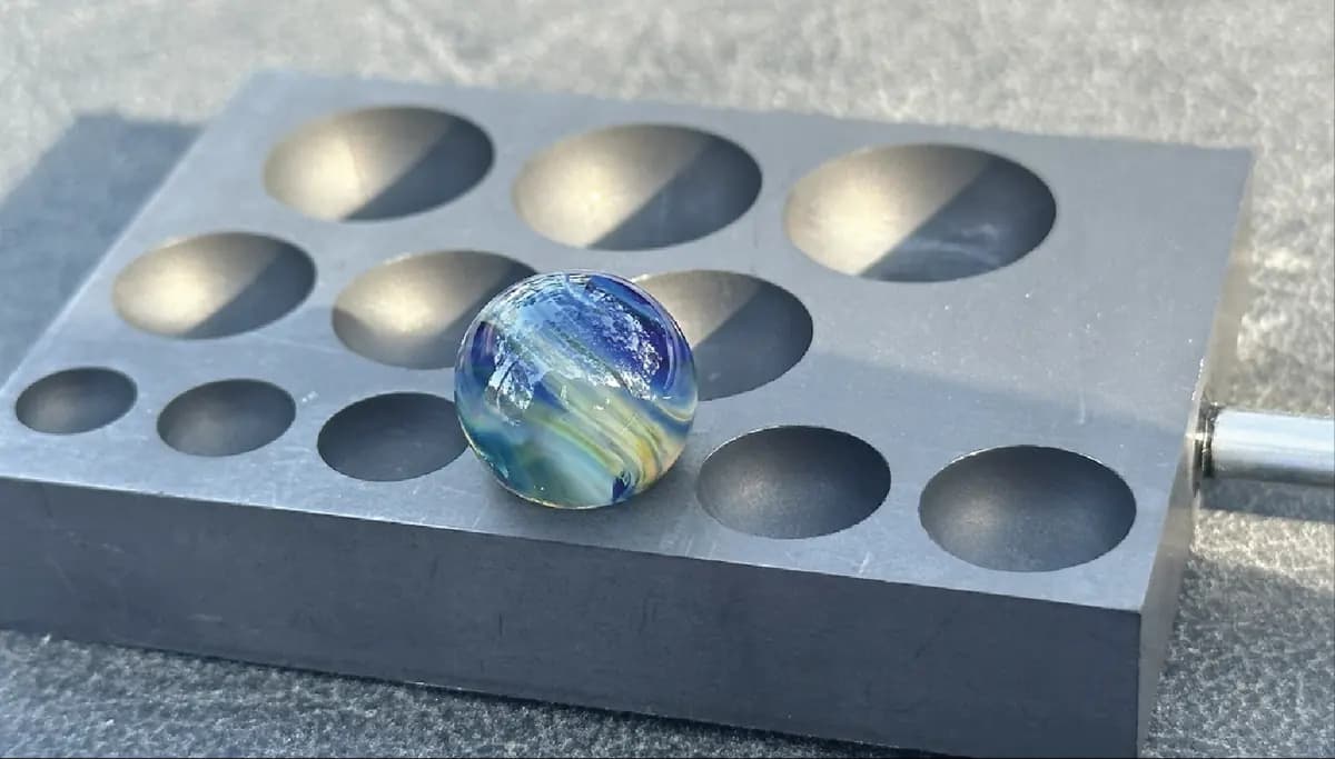 Glass marble resting in a graphite mold